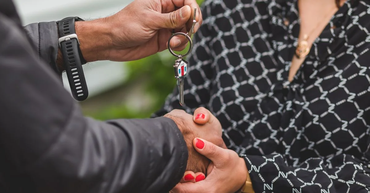 Un gros plan de mains échangeant une clé de maison, symbolisant des transactions immobilières ou l'accession à la propriété.
