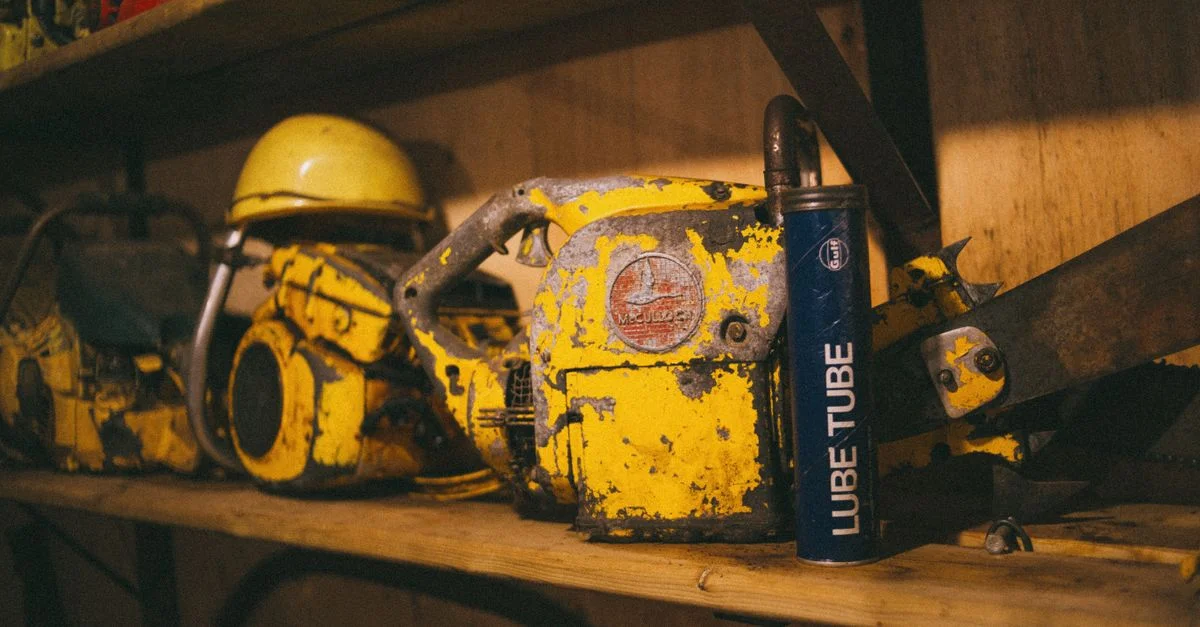 Scène de workshop rustique avec des tronçonneuses vintage et un casque de sécurité sur une étagère en bois.