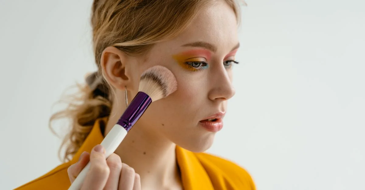 Femme utilisant un pinceau à maquillage pour appliquer du fard à joues, mettant en valeur la beauté et les cosmétiques à l'intérieur.