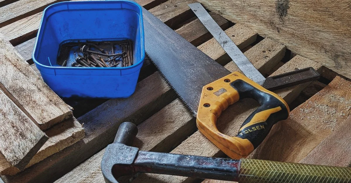 Gros plan sur des outils de menuiserie comprenant un marteau, une scie et des clous sur un lieu de travail.