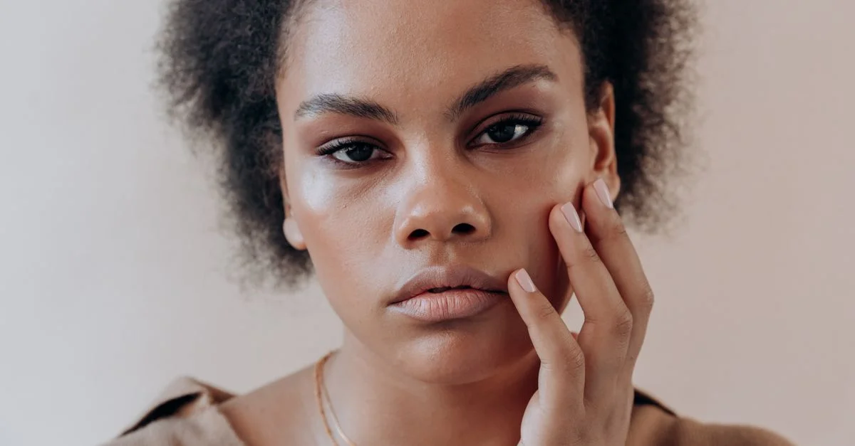 Portrait en gros plan d'une femme avec des cheveux afro, exprimant une introspection réfléchie.