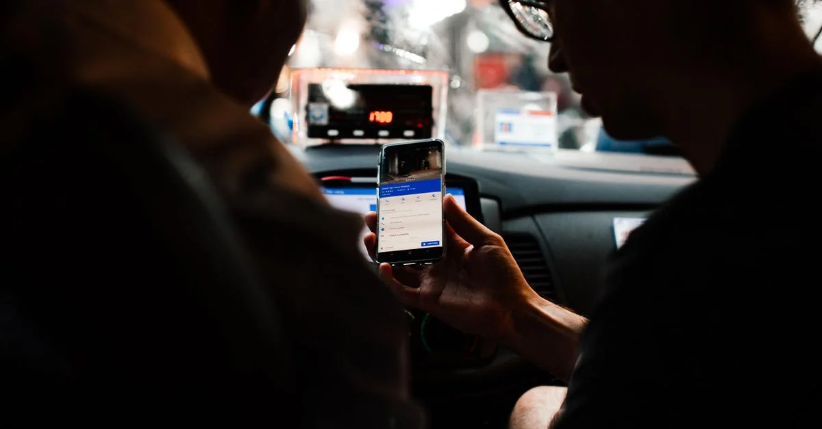Deux personnes utilisant un smartphone pour se diriger dans une voiture la nuit.