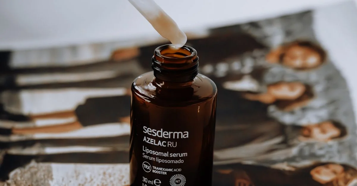 Un flacon de sérum liposomal muni d'un compte-gouttes, posé sur un magazine à fond flou.